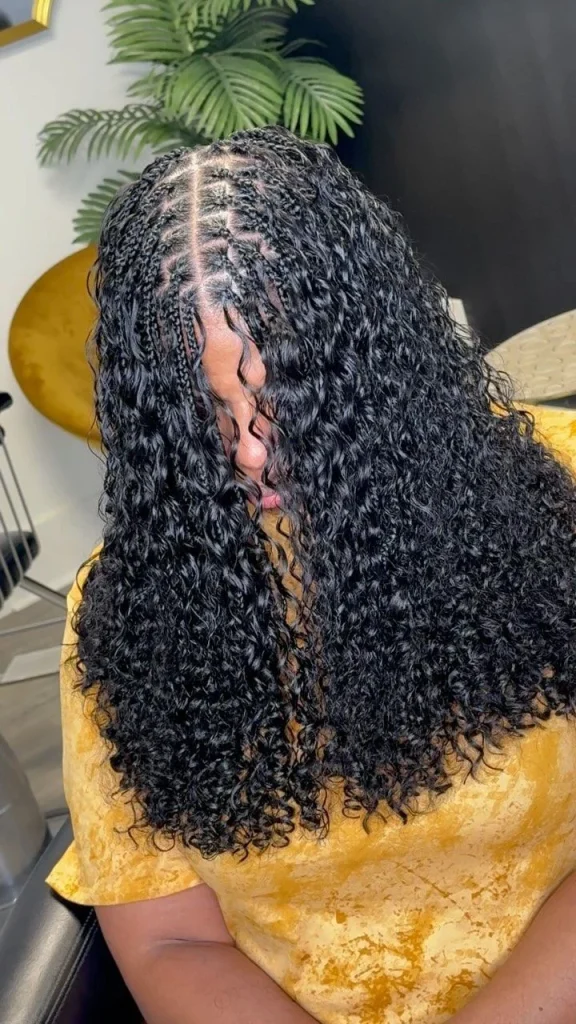 Black woman wearing deep wave braids with soft wavy curls and knotless braids in the UK
